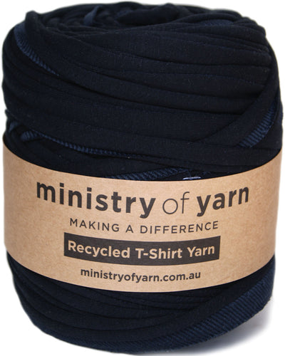 A roll of dark navy blue recycled t-shirt yarn wrapped with a brown paper label that reads 'ministry of yarn'.