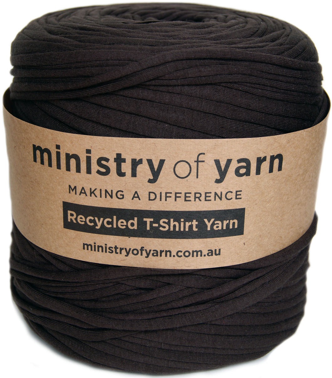 A large spool of dark brown recycled t-shirt yarn wrapped with a brown paper label that reads 'ministry of yarn'.