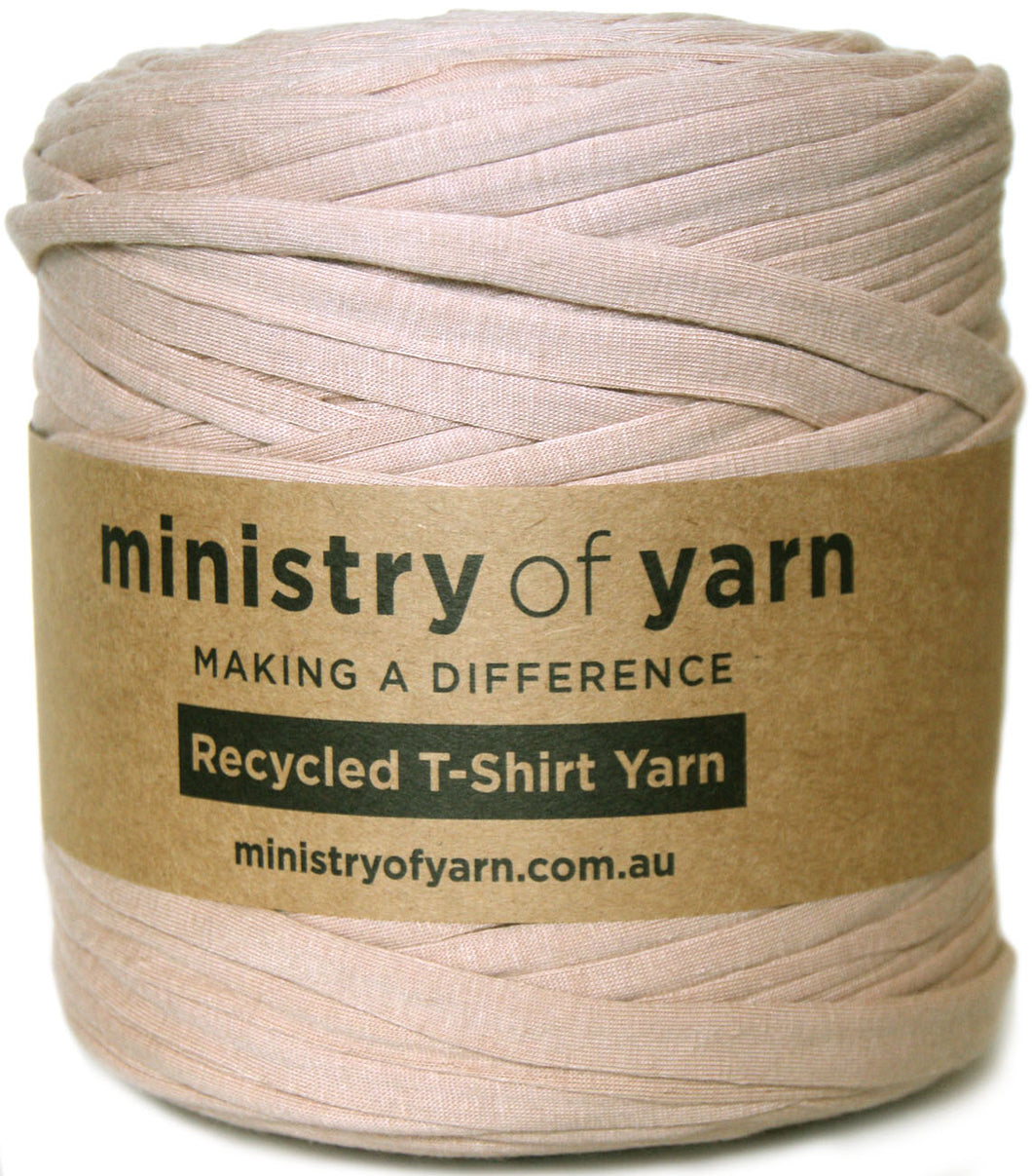A spool of light brown recycled T-shirt yarn wrapped with a brown kraft paper label that reads 'ministry of yarn'.