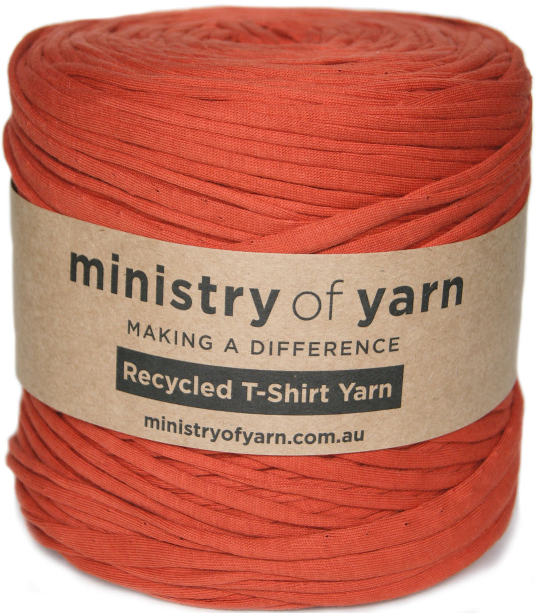 A skein of rust-colored recycled T-shirt yarn wrapped in a brown paper label that reads 'ministry of yarn'.