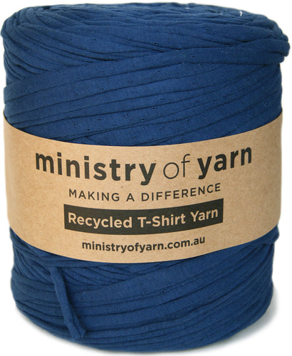 A large spool of navy blue recycled t-shirt yarn wrapped with a brown kraft paper label that reads 'ministry of yarn'.