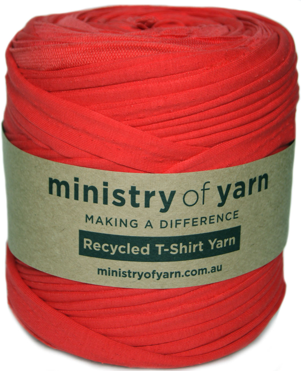 A roll of bright red recycled T-shirt yarn with a kraft paper label that reads 'ministry of yarn' and 'Recycled T-Shirt Yarn'.