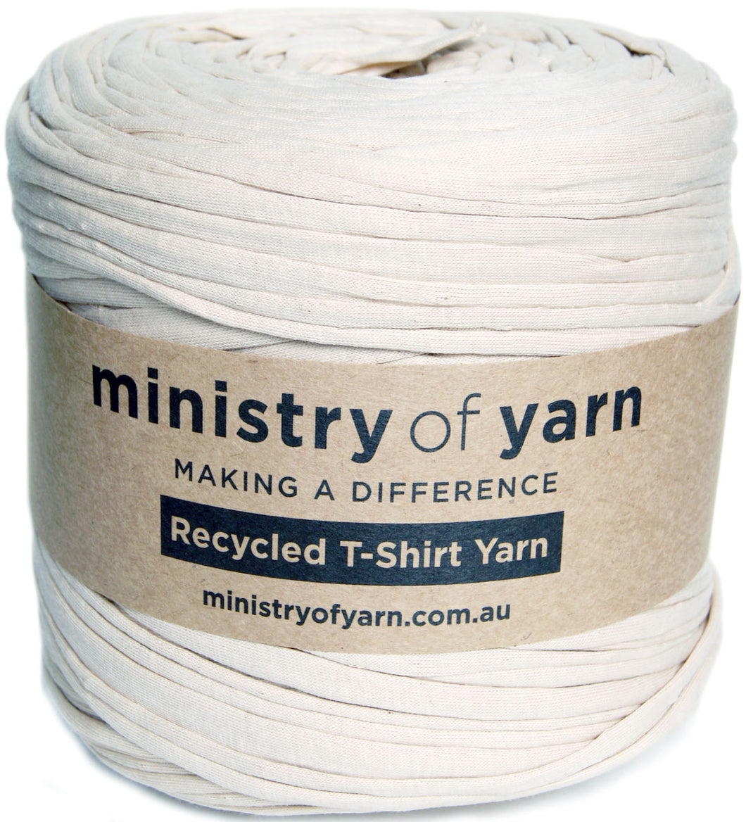 A spool of off-white beige recycled T-shirt yarn wrapped in a brown kraft paper label that reads 'ministry of yarn'.