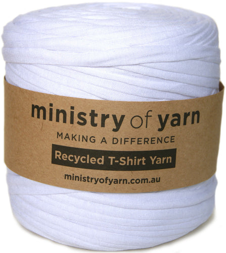 A white spool of Ministry of Yarn recycled T-shirt yarn wrapped with a brown kraft paper label, shown against a plain white background.