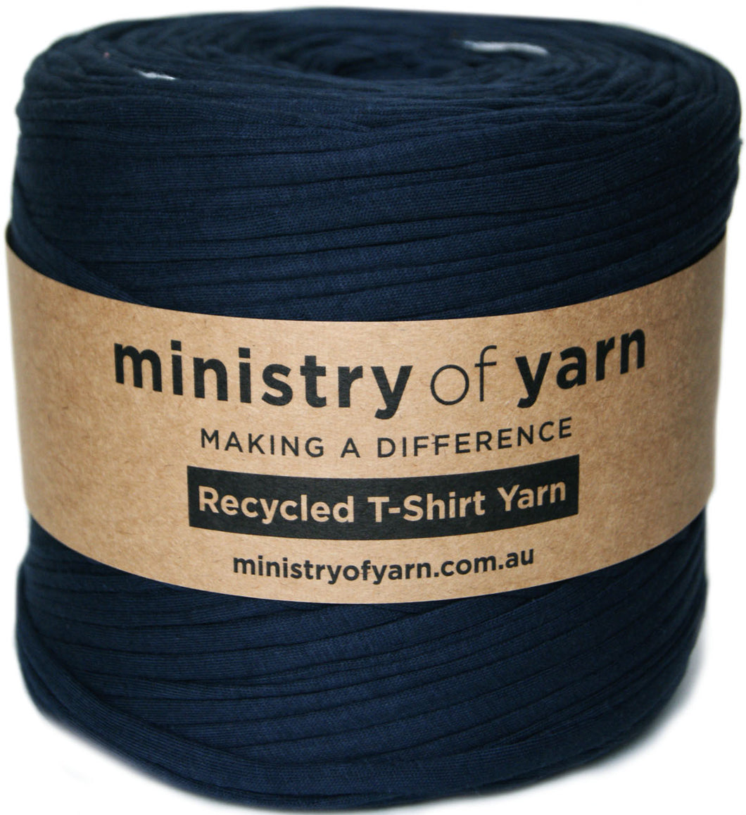 A roll of navy blue recycled T-shirt yarn wrapped with a brown kraft paper label that reads 'ministry of yarn'.
