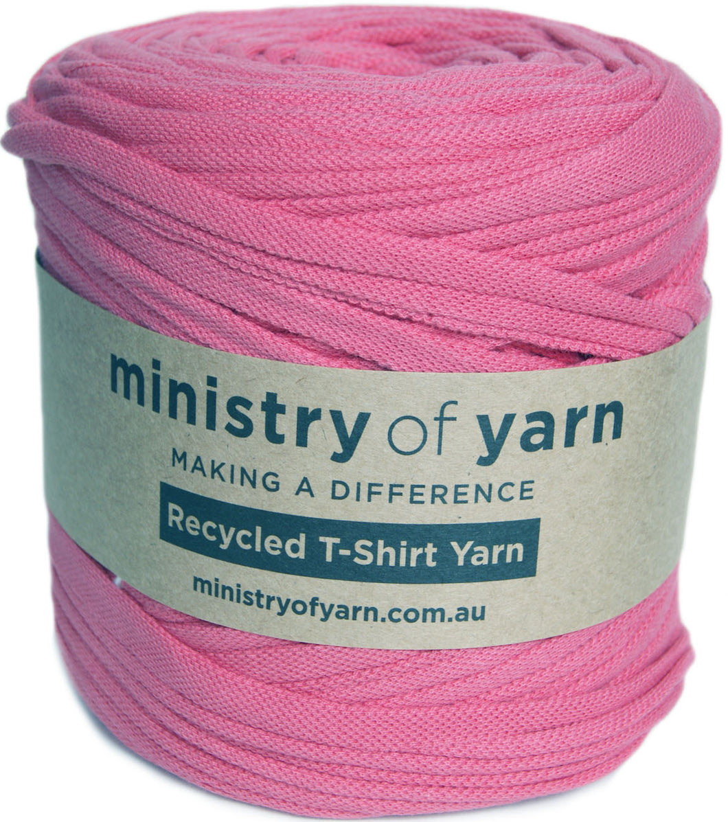 A pink roll of Ministry of Yarn recycled T-shirt yarn with a beige paper label, shown on a white background.