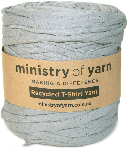A spool of light gray recycled T-shirt yarn wrapped in a brown kraft paper label that reads 'ministry of yarn'.