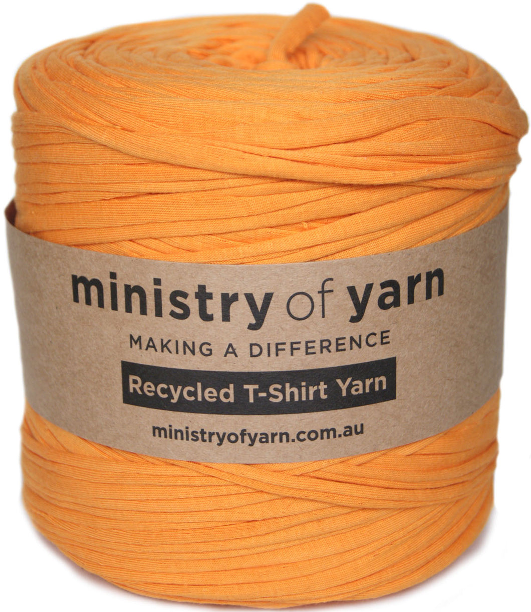 A skein of orange recycled T-shirt yarn wrapped in a brown paper label that reads 'ministry of yarn' and 'Recycled T-Shirt Yarn'.