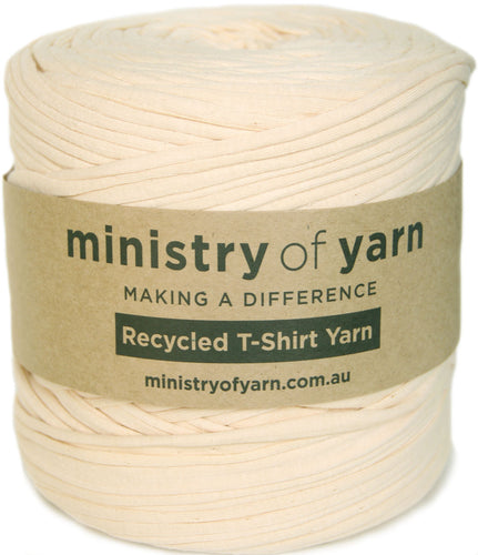 A spool of cream-colored recycled T-shirt yarn wrapped with a brown kraft paper label that reads 'ministry of yarn'.