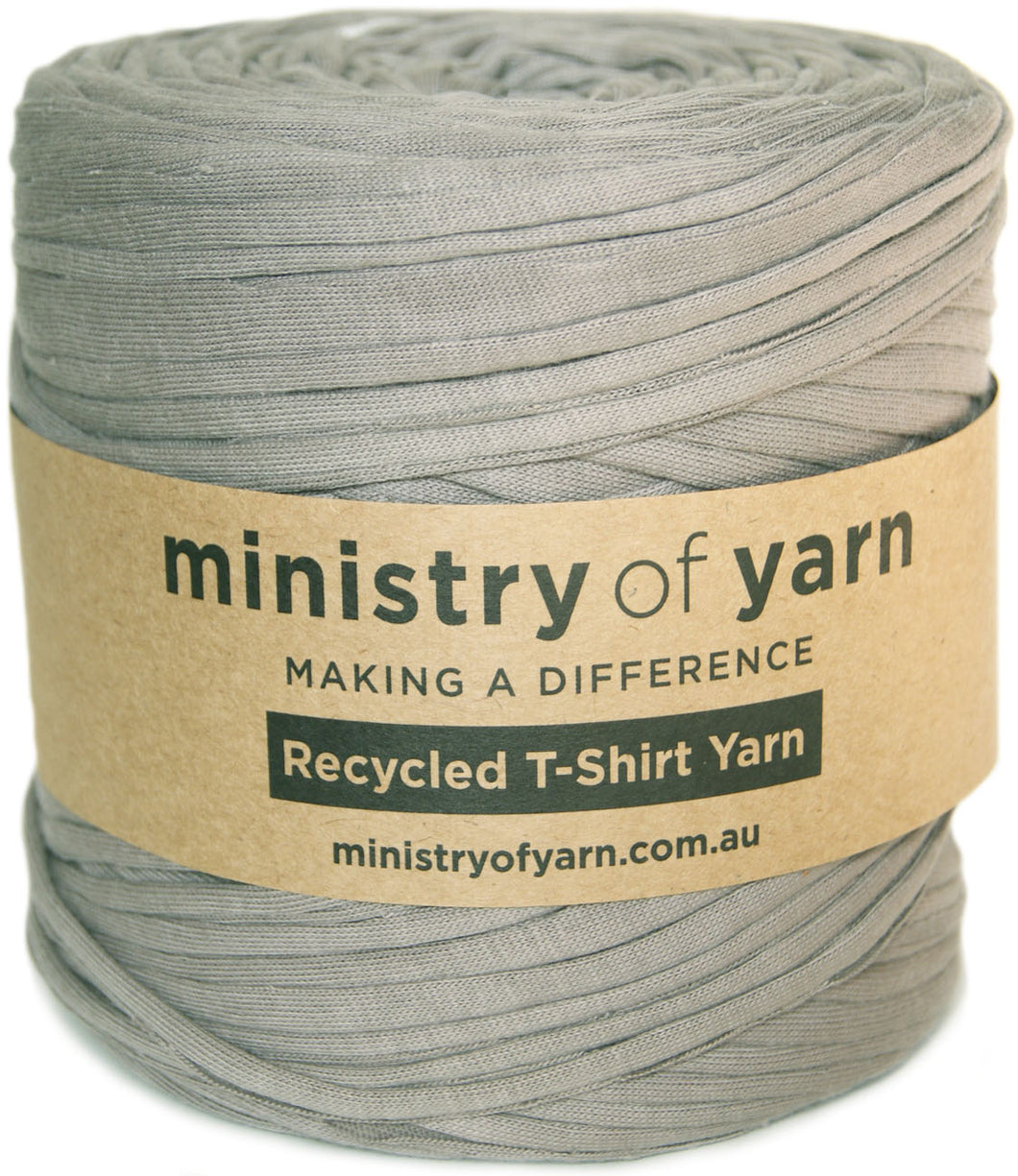 A roll of gray recycled T-shirt yarn wrapped with a brown paper label that reads 'ministry of yarn' and 'Recycled T-Shirt Yarn'.