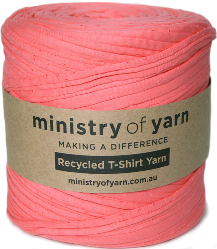 A spool of coral pink recycled T-shirt yarn wrapped with a brown paper label that reads 'ministry of yarn' and 'Recycled T-Shirt Yarn'.