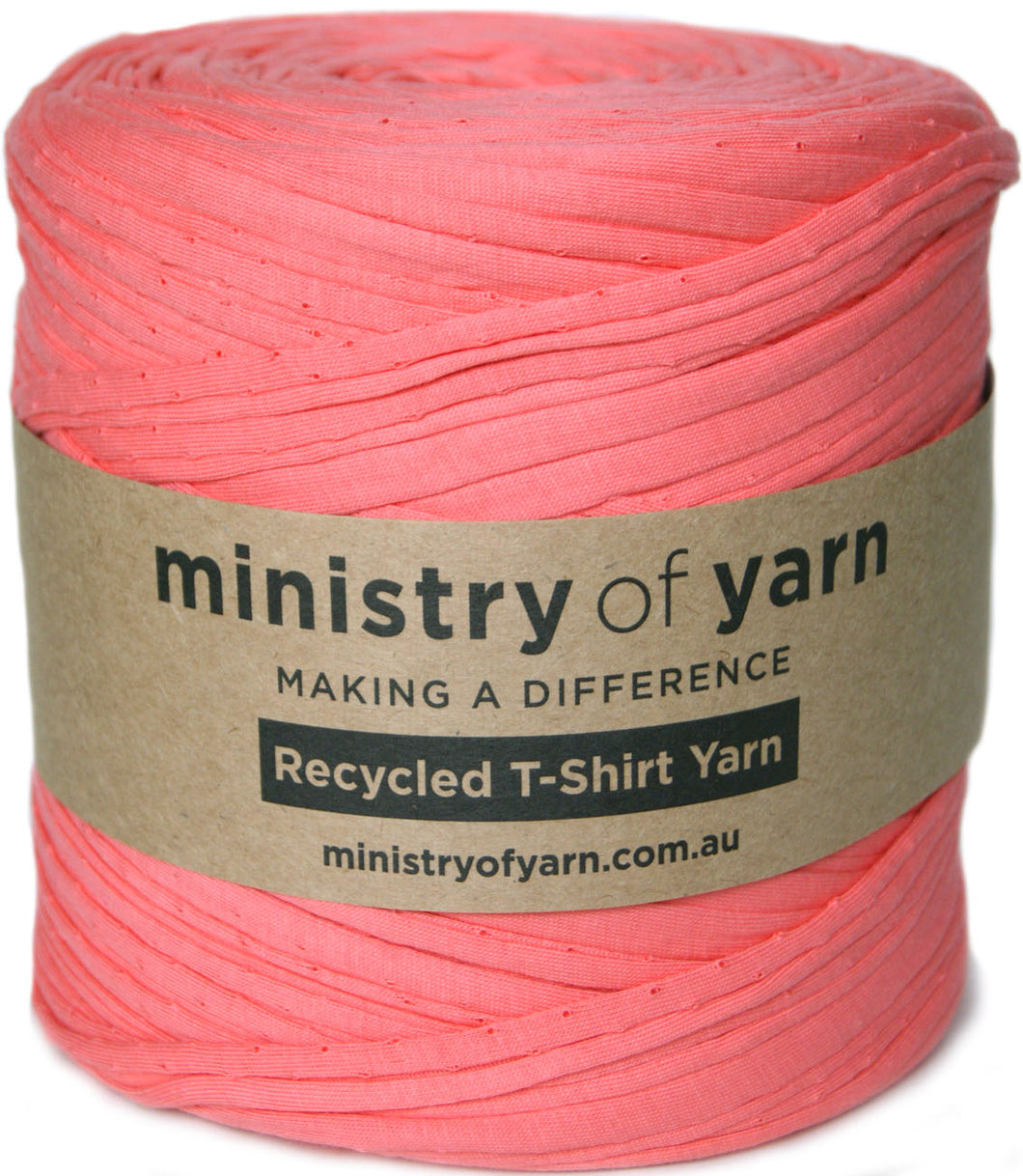 A spool of coral pink recycled T-shirt yarn wrapped with a brown paper label that reads 'ministry of yarn' and 'Recycled T-Shirt Yarn'.
