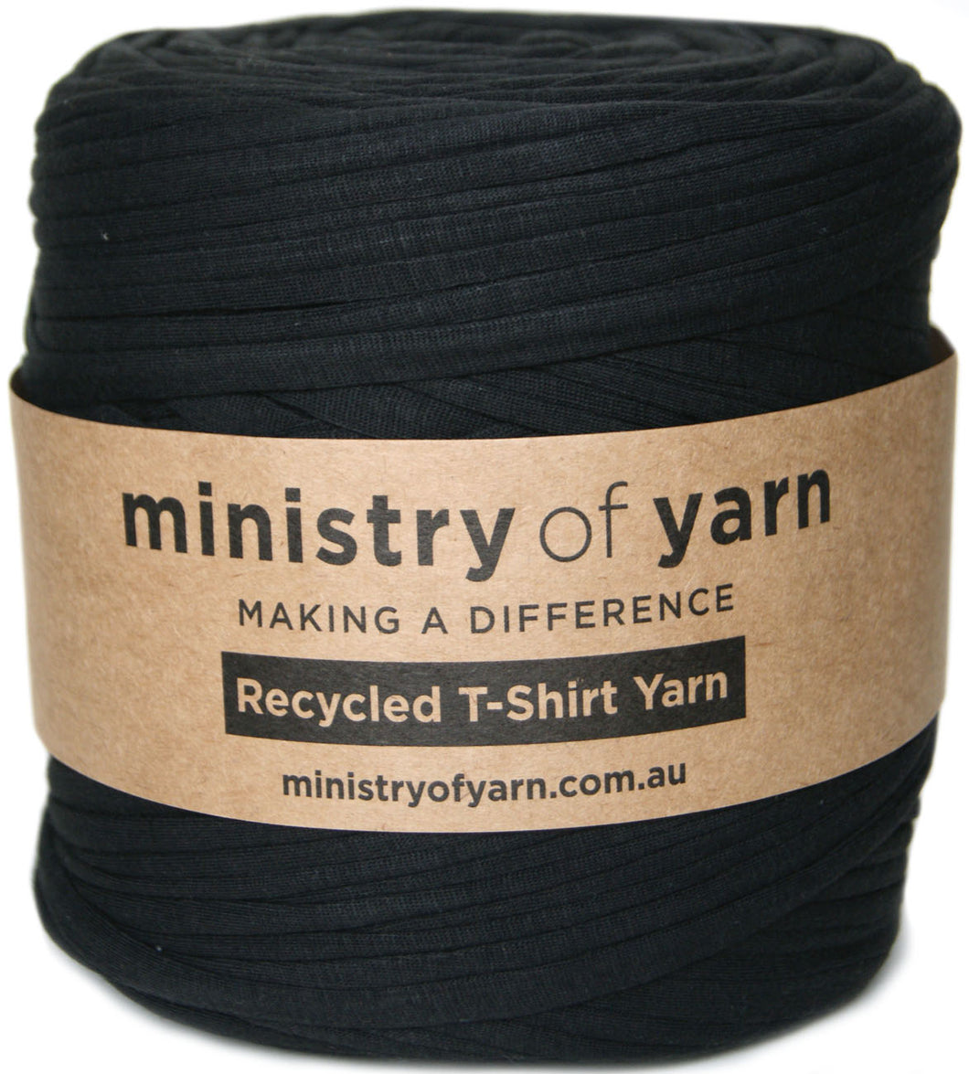 A large spool of black recycled T-shirt yarn wrapped with a brown paper label that reads 'ministry of yarn' and 'Recycled T-Shirt Yarn'.