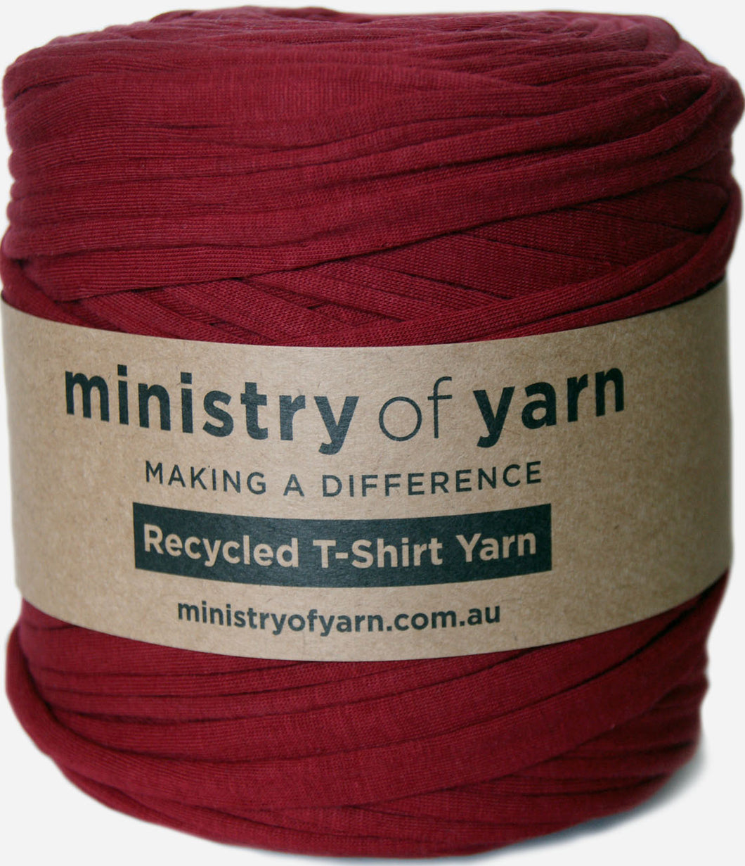 A ball of deep red recycled t-shirt yarn wrapped in a brown paper label that reads 'ministry of yarn'.