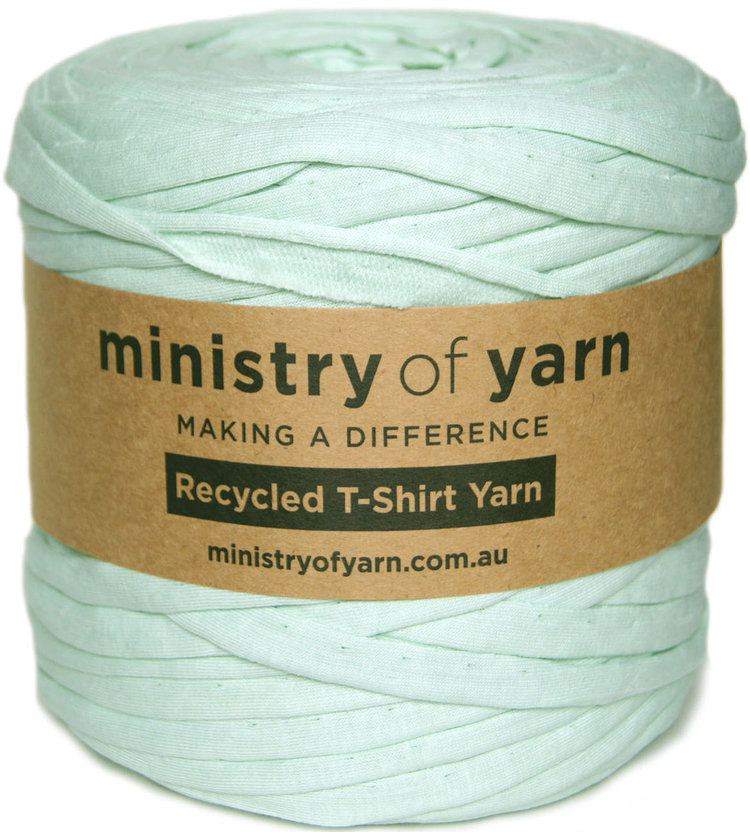 A spool of mint green recycled T-shirt yarn wrapped with a brown paper label that reads 'ministry of yarn'.