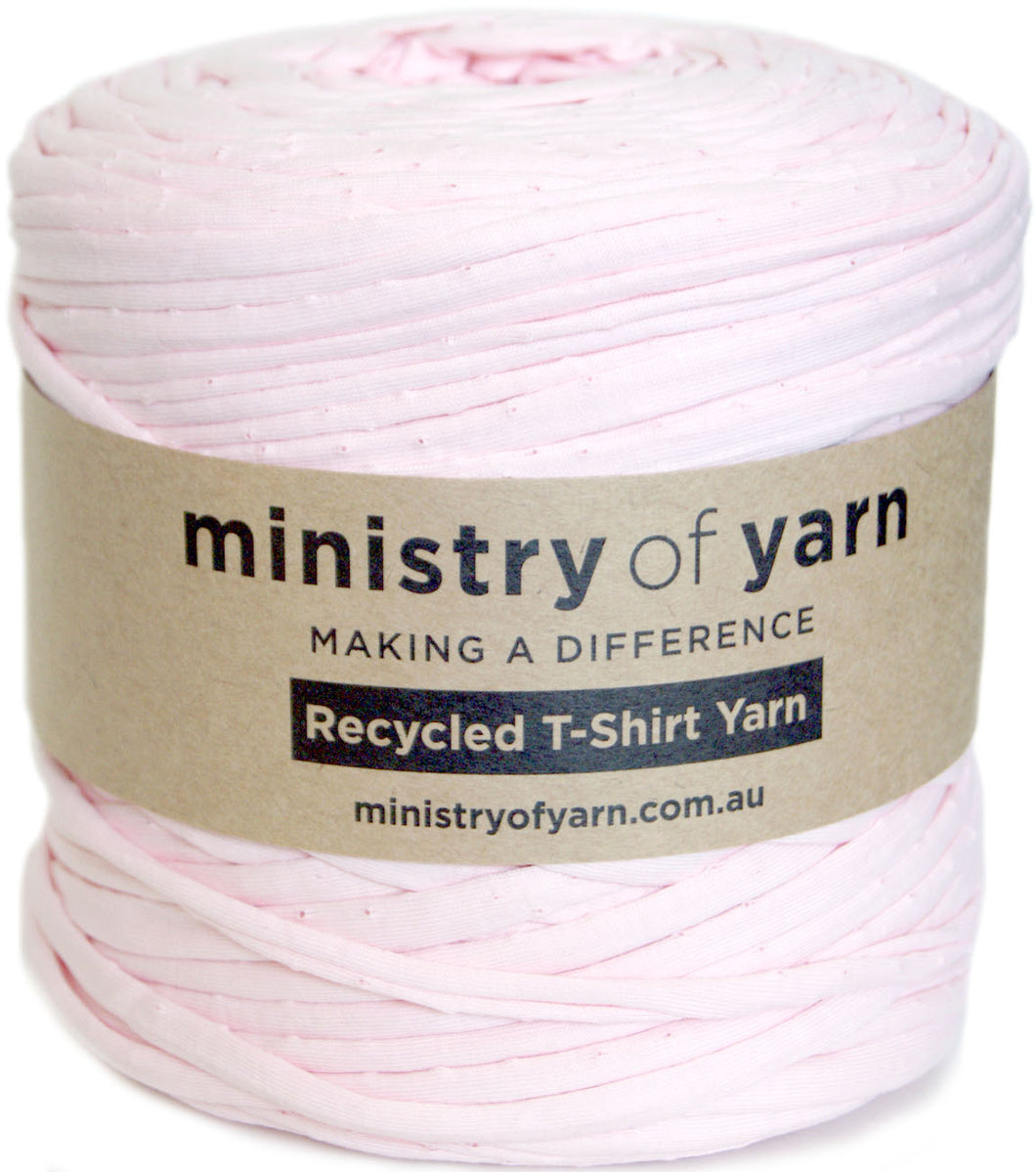 A roll of light pink recycled T-shirt yarn wrapped with a brown paper label that reads 'ministry of yarn'.