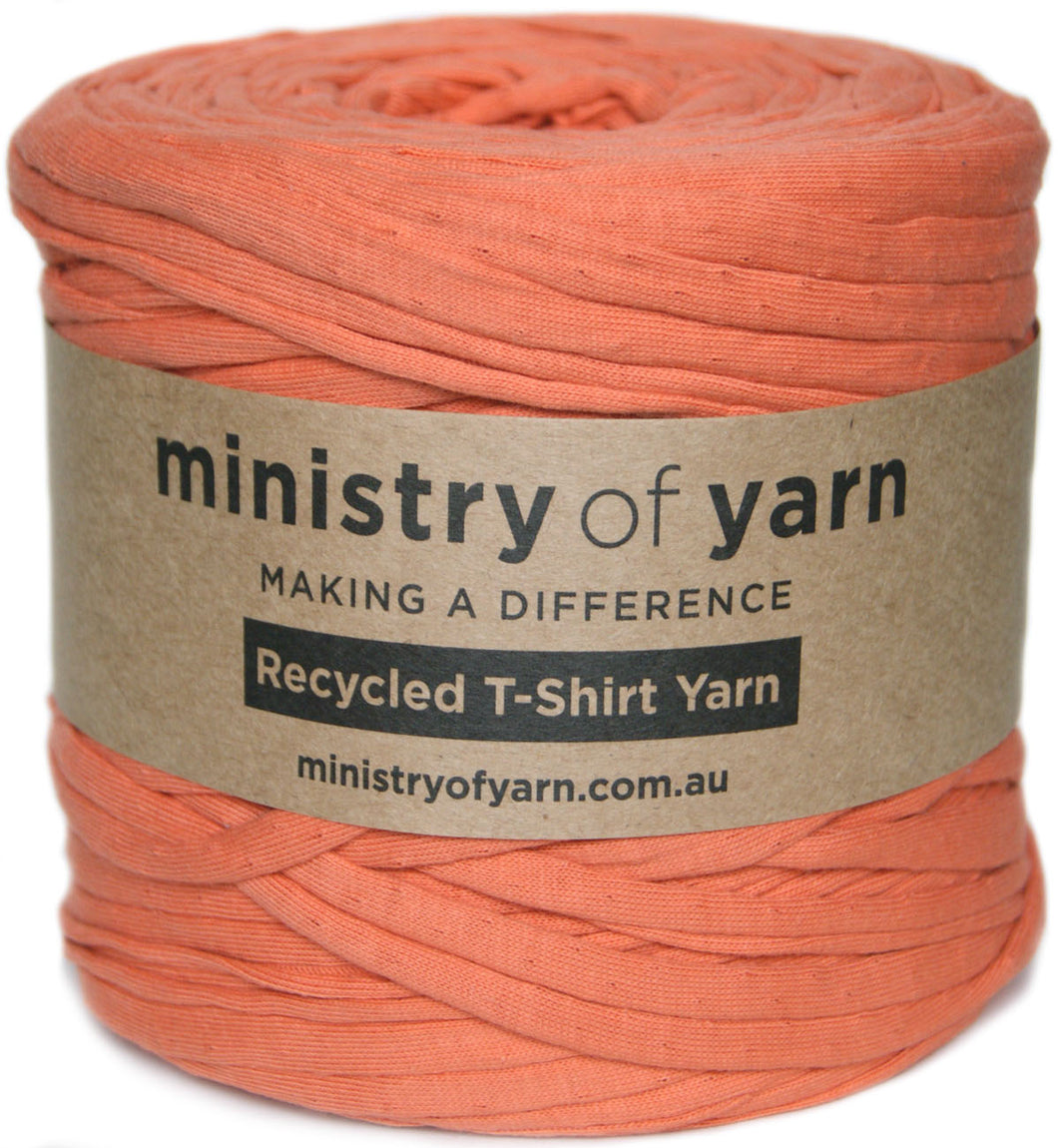 A skein of coral orange recycled T-shirt yarn wrapped in a brown paper label that reads 'ministry of yarn' and 'Recycled T-Shirt Yarn'.