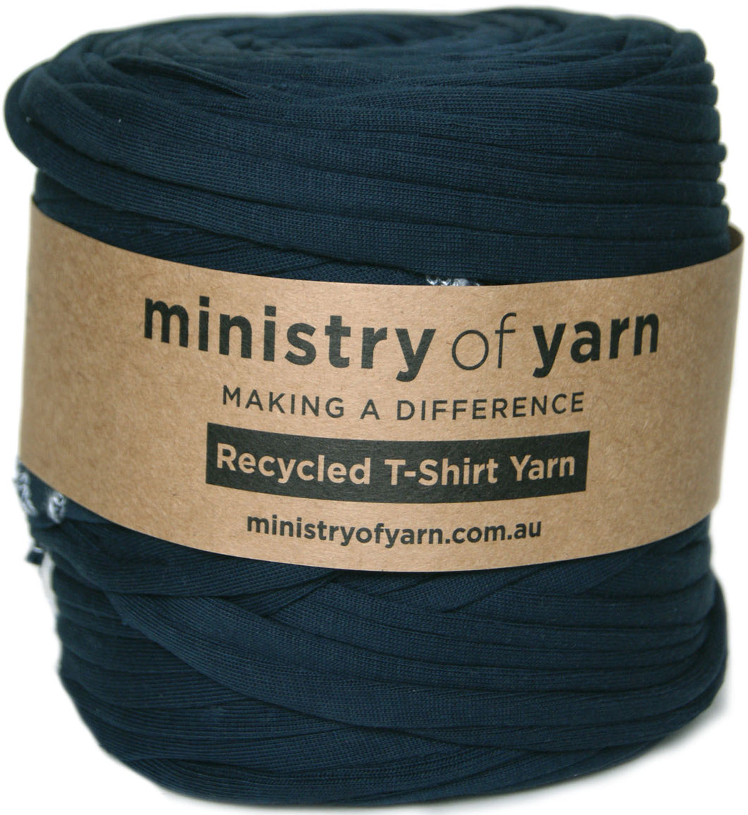 A roll of navy blue recycled T-shirt yarn wrapped with a brown kraft paper label that reads 'ministry of yarn'.