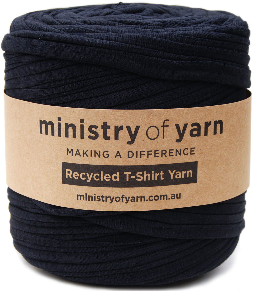 A roll of black recycled T-shirt yarn wrapped with a brown kraft paper label that reads 'ministry of yarn'.