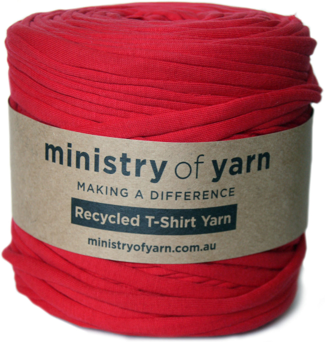 A roll of bright red recycled T-shirt yarn wrapped with a brown paper label that reads 'ministry of yarn'.