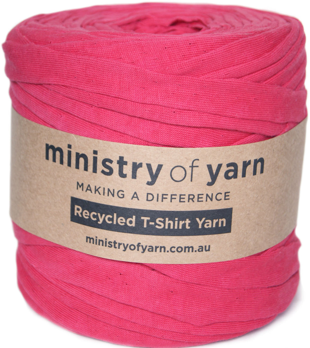 A skein of bright pink recycled T-shirt yarn wrapped in a brown kraft paper label that reads 'ministry of yarn'.
