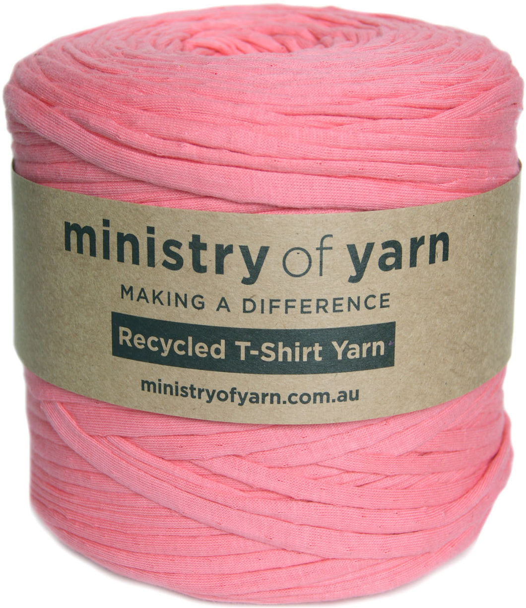A pink roll of t-shirt yarn wrapped with a brown paper label that reads 'ministry of yarn' and 'Recycled T-Shirt Yarn'.