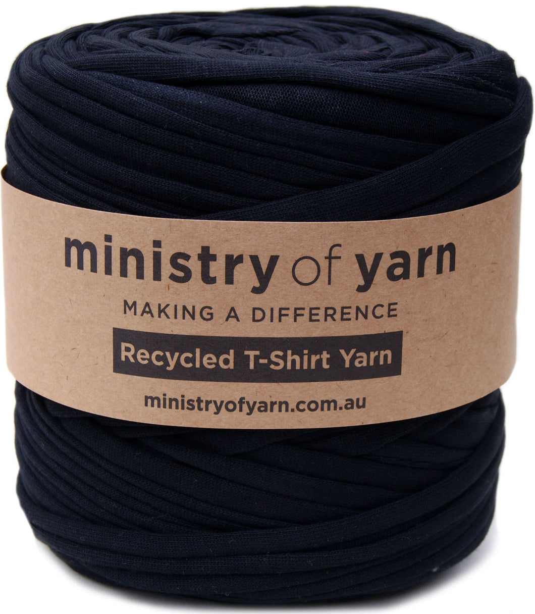 A roll of Ministry of Yarn recycled T-shirt yarn in black, wrapped with a brown kraft paper label.