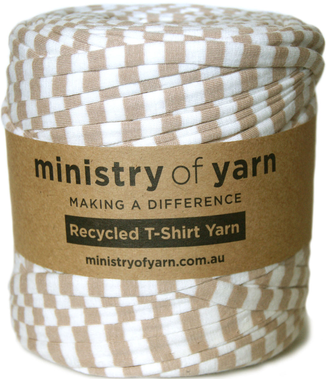 A spool of Ministry of Yarn recycled T-shirt yarn with a brown and white checkered pattern, wrapped in a brown kraft paper label.