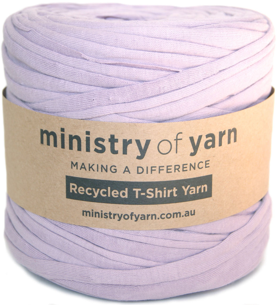 A roll of light lavender purple recycled T-shirt yarn wrapped with a brown kraft paper label that reads 'ministry of yarn'.